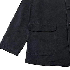 May include: A close-up of a dark navy blue jacket with a single pocket and three buttons. The jacket has long sleeves and a classic design, suitable for various occasions. The fabric appears to be a durable material.