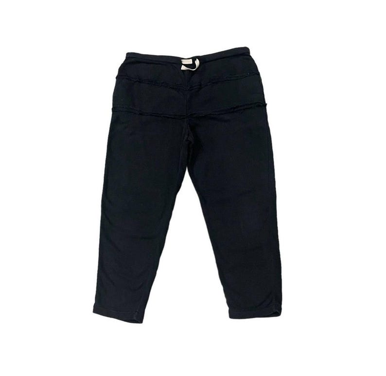 Puede incluir: Pantalones cortos negros con cintura con cord&oacute;n. Los pantalones tienen un dise&ntilde;o &uacute;nico con costuras horizontales en la parte delantera. La tela parece ser un material suave y c&oacute;modo. Adecuado para uso casual.