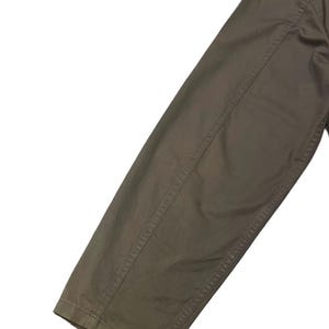 May include: Close-up of a section of a brown garment, likely a jacket or coat sleeve. The fabric appears to be a sturdy material, with visible stitching along the seams. The color is a muted, earthy brown.