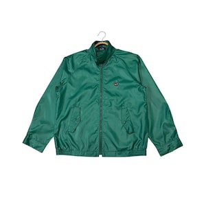 May include: Emerald green jacket with a stand-up collar, a full-length zipper, and two front pockets. The jacket has a small logo on the chest and elastic cuffs and waistband. The jacket is hanging on a hanger.