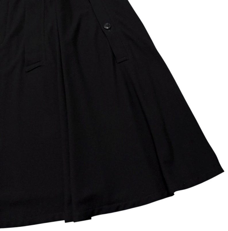 May include: A black skirt with a button closure and a pleated design. The skirt has a flowing, A-line silhouette, and is made of a smooth, opaque fabric. The skirt's hemline is visible in the image.