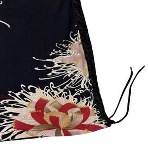 May include: Black fabric featuring a large floral design in red, white, and gold. The design is on the lower portion of the fabric. The fabric has a drawstring and a black trim.