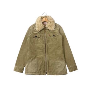 May include: A corduroy jacket in a muted olive green color, featuring a faux fur collar and a zip-up front. The jacket has two chest pockets and two lower pockets. The jacket is hanging on a wooden hanger.