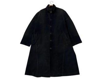 May include: A long, black corduroy coat with a button-up front and a collar. The coat has long sleeves and two front pockets. The coat is hanging on a wooden hanger against a white background. The coat is a classic style.