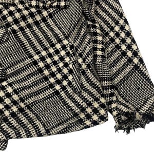 May include: Black and white plaid jacket with a frayed hem. The jacket features a classic houndstooth pattern and a double-breasted design. The fabric appears to be a woven material, suitable for cooler weather. The overall style is a timeless, versatile piece.
