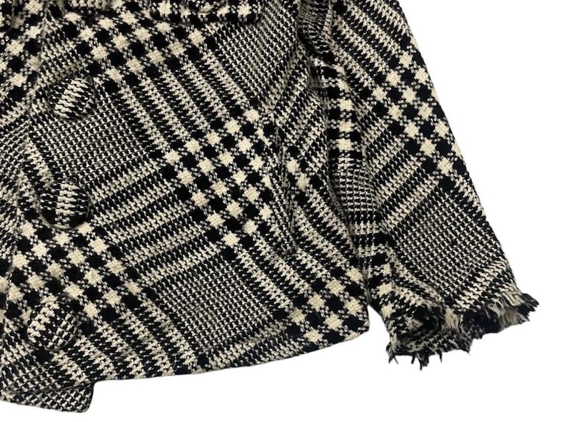 May include: Black and white plaid jacket with a frayed hem. The jacket features a classic houndstooth pattern and a double-breasted design. The fabric appears to be a woven material, suitable for cooler weather. The overall style is a timeless, versatile piece.