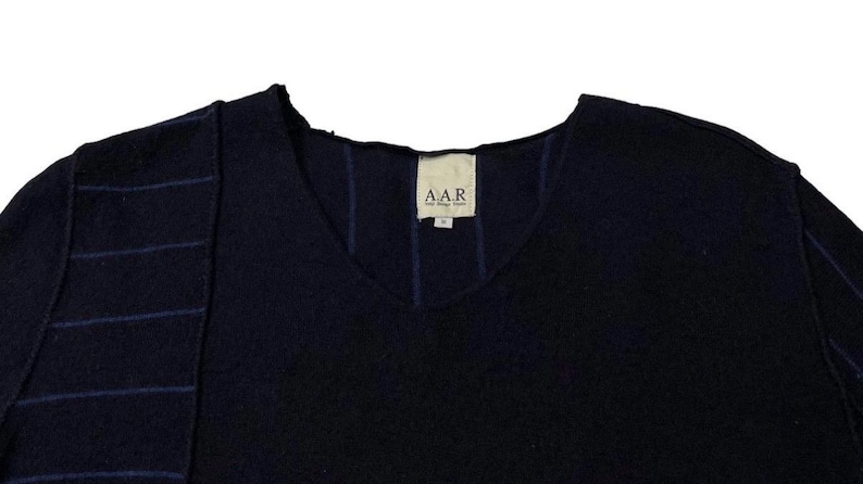 Puede incluir: Un su&eacute;ter de cuello en V azul marino con un dise&ntilde;o &uacute;nico. El su&eacute;ter presenta un panel en contraste en el lado izquierdo con rayas azules horizontales. La etiqueta dice "A.A.R."