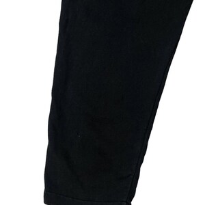 Puede incluir: Primer plano de una pernera de pantal&oacute;n negra. La tela es de color negro oscuro liso. El dobladillo inferior est&aacute; doblado. Los pantalones est&aacute;n hechos de un material suave.