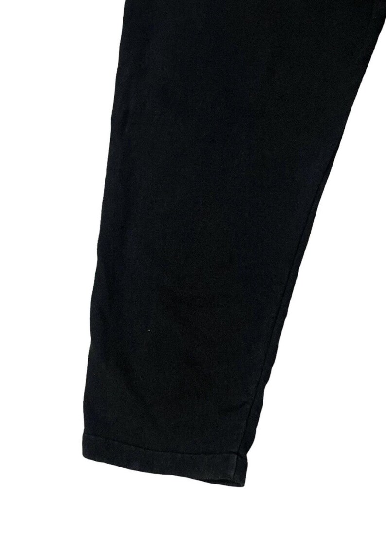 Puede incluir: Primer plano de una pernera de pantal&oacute;n negra. La tela es de color negro oscuro liso. El dobladillo inferior est&aacute; doblado. Los pantalones est&aacute;n hechos de un material suave.