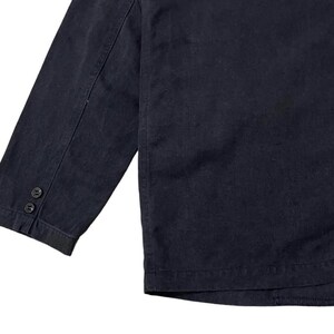 May include: A dark navy blue blazer with a three-button sleeve detail. The blazer has a classic design with a tailored fit. The fabric appears to be a sturdy, woven material, suitable for a variety of occasions.