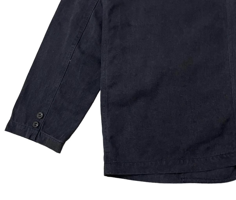 May include: A dark navy blue blazer with a three-button sleeve detail. The blazer has a classic design with a tailored fit. The fabric appears to be a sturdy, woven material, suitable for a variety of occasions.