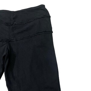 Puede incluir: Pantalones negros con tres costuras horizontales deshilachadas en la parte superior. Los pantalones parecen estar hechos de una tela oscura y suave. El dise&ntilde;o es sencillo e informal.