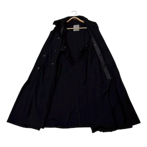 May include: A black trench coat with a wide, open design, revealing the interior lining and button details. The coat is hanging on a wooden hanger, showcasing its full length and tailored silhouette. The coat has a classic, timeless style.