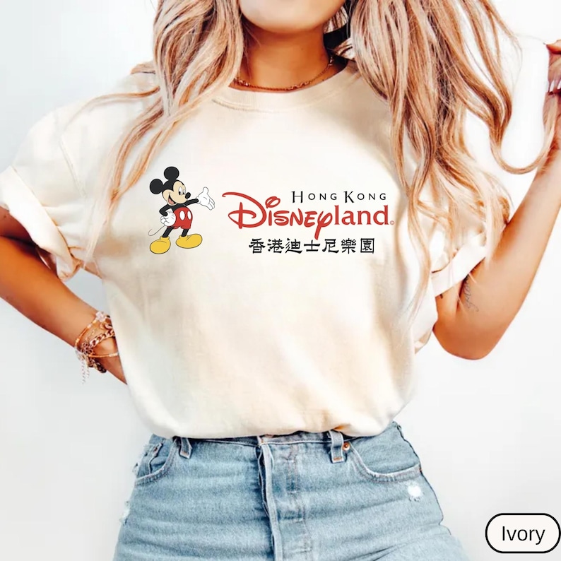 Op de afbeelding: Ivoor kleurig T-shirt met Mickey Mouse en de tekst "Hong Kong Disneyland" in het Engels en Chinees. Mickey Mouse is afgebeeld in zijn klassieke pose. Het shirt heeft een lichtcr&egrave;mekleur.