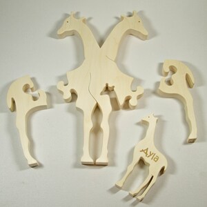 Op de afbeelding: Houten puzzel met vijf stukken die samen een giraffe vormen. De giraffe heeft de naam "Ayla" gegraveerd op zijn lichaam.