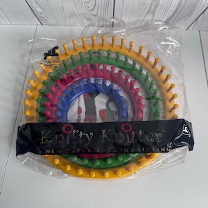 May include: A set of four circular plastic knitting looms in yellow, green, pink, and blue, nested inside a clear plastic bag. The black label features the text Knifty Knitter, A NEW EXPERIENCE IN KNITTING, and the Provo Craft logo.
