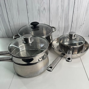 May include: A set of stainless steel cookware including a large stockpot with a glass lid, a steamer insert with a glass lid, and a smaller saucepan with a glass lid. Each lid features a metal handle and the brand name Chefs Pride is visible.