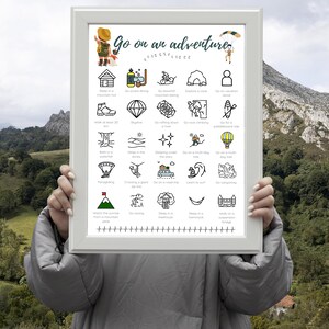 May include: A framed print featuring the words "Go on an adventure" and illustrated icons depicting outdoor activities. The print is held against a backdrop of mountains and lush greenery.