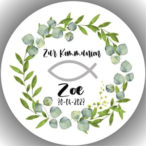 Könnte beinhalten: Ein runder, weißer Aufkleber mit einem Eukalyptus-Kranz. Der Text "Zur Kommunion" steht über einem grauen Fischsymbol, darunter "Zoe" und das Datum "30-04-2023". Geeignet für eine religiöse Feier.