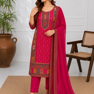May include: A vibrant fuchsia three-piece ensemble consisting of a knee-length tunic with intricate geometric patterns, matching straight-leg trousers, and a long, solid-colored sheer dupatta featuring a decorative border along the edges.