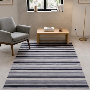 May include: A rectangular area rug featuring a horizontal striped pattern in varying shades of charcoal gray, light gray, and white. The rug has a textured appearance with a short fringe detail along the shorter edges, covering the floor space.