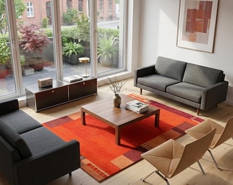 May include: A living room featuring two dark gray sofas, a square wooden coffee table, and two tan leather chairs. A large orange area rug with geometric patterns covers the light wood floor. A low dark cabinet sits near a window with plants.