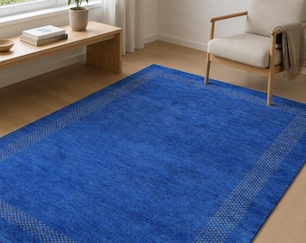 May include: A rectangular area rug in a vibrant royal blue color featuring a subtle, repeating geometric dot pattern along the border. The rug has a short, dense pile texture and is positioned flat on a light-colored wooden floor surface.