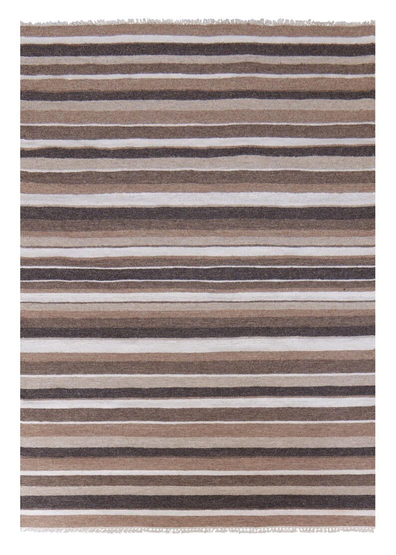Puede incluir: Una alfombra rectangular tejida con un patr&oacute;n repetitivo de rayas horizontales en varios tonos de marr&oacute;n, beige, topo y blanco. La alfombra tiene una superficie texturizada e incluye flecos cortos y deshilachados en los bordes superior e inferior.