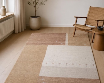 May include: A rectangular area rug featuring a geometric color-block pattern in shades of beige, cream, and tan. The design includes sections with subtle, small-scale floral motifs and textured, solid-colored panels arranged in a modern composition.