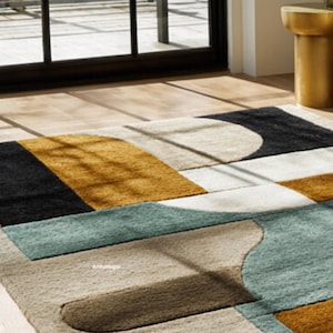May include: Geometric patterned area rug featuring a mix of colors including black, gold, teal, and beige. The rug has a modern design with various shapes and sections. The rug is placed on a wooden floor near a window.