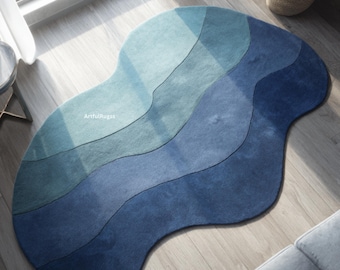 May include: A blue area rug with a unique, organic shape. The rug features a gradient of blue hues, from light teal to deep navy, with wavy lines creating a layered effect. The text "ArtfulRugss" is visible on the rug.