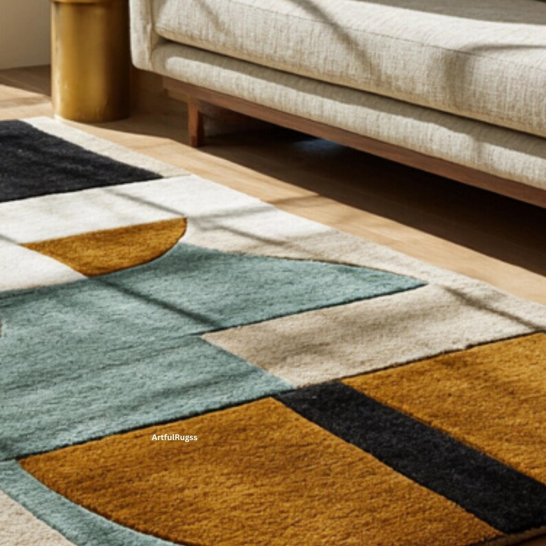 May include: Geometric patterned area rug with a mix of colors including teal, mustard yellow, black, and beige. The rug is rectangular and features a modern design with various shapes. The text "ArtfulRugss" is visible on the rug.