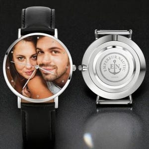 May include: A silver wristwatch with a black leather band, displaying a color photo of a couple on the watch face. The watch's back features the text "EMPEREUR NAUTIC LONDON" and an anchor logo.