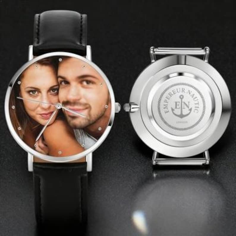 May include: A silver wristwatch with a black leather band, displaying a color photo of a couple on the watch face. The watch's back features the text "EMPEREUR NAUTIC LONDON" and an anchor logo.
