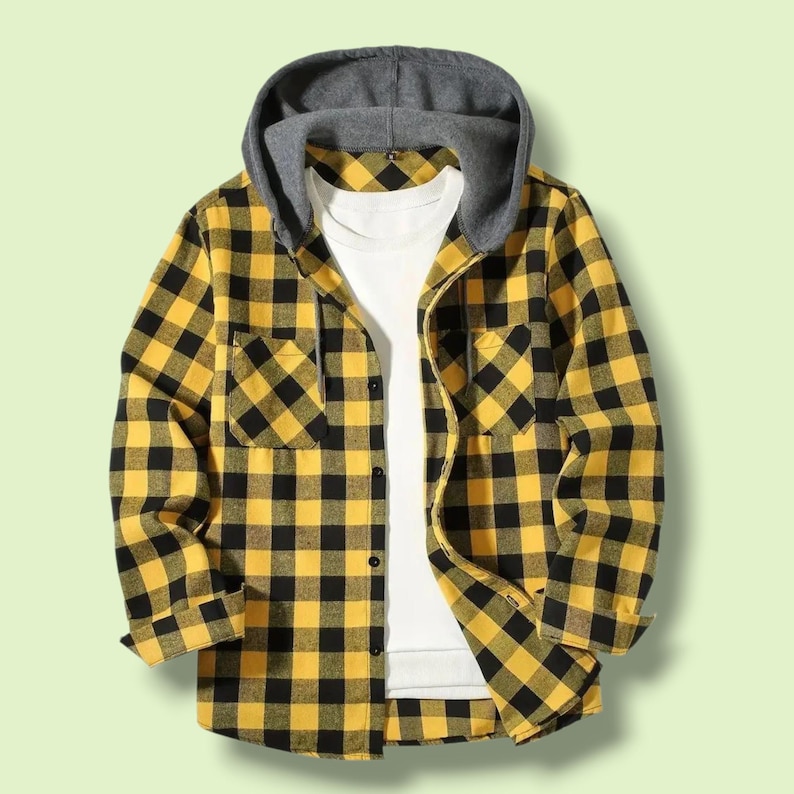 May include: A long-sleeve button-up shirt featuring a yellow and black buffalo plaid pattern. The shirt includes a solid grey attached hood with drawstrings and is layered over a plain white t-shirt. It has a single chest pocket on the left side.