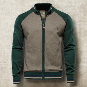 May include: A green and grey zip-up jacket with a stand-up collar. The jacket features green sleeves and a grey body, with a small logo on the chest. The collar and cuffs have striped detailing. The jacket has a full-length zip.
