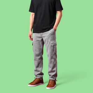 Könnte beinhalten: Ein schwarzes kurzärmeliges T-Shirt kombiniert mit einer grauen Jogginghose mit einer Cargotasche an der Seite und braunen Ledersneakern mit weißen Sohlen. Die Hose hat eine lockere Passform und ein Kordelzugdetail am Beinabschluss.