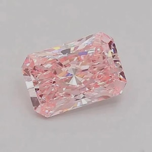 May include: A rectangular radiant-cut gemstone with a light pink hue. The stone features numerous triangular and trapezoidal facets that create a complex, reflective pattern across its surface, showcasing a high level of clarity and brilliance.