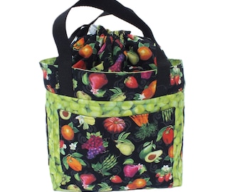 May include: A black and green reusable grocery tote bag with a drawstring top and a print of various fruits and vegetables. The bag has two black handles.