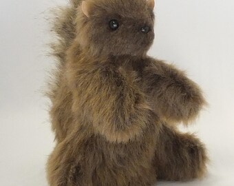 May include: A brown plush squirrel toy with a fluffy tail, small ears, and black eyes. The stuffed animal is sitting upright with its arms outstretched, showcasing its soft, textured fur. A cute and cuddly woodland creature.