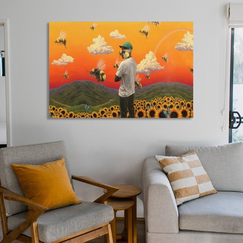 May include: A large canvas art print depicts a person in a white shirt and green cap standing in a field of sunflowers. The background features a sunset sky, clouds, and bees. A rainbow arcs across the sky.