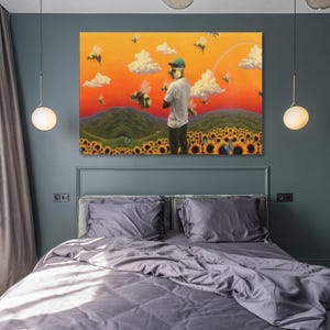 May include: A large, framed canvas art print depicting a surreal landscape with a person standing in a field of sunflowers, surrounded by bees. The background features rolling green hills, fluffy clouds, and an orange and yellow sky.
