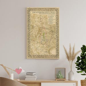 Puede incluir: Un mapa vintage enmarcado titulado "The Lonesome Dove Trail" y "The Comanche Moon Wars". El mapa presenta una representaci&oacute;n detallada de los senderos con un borde decorativo. El mapa se exhibe en una pared de color neutro.