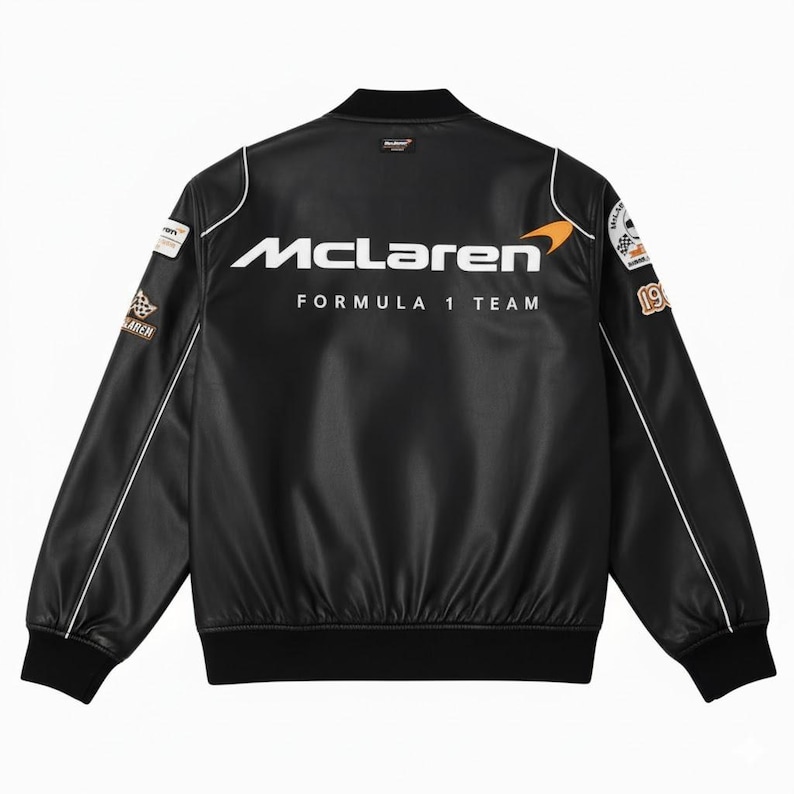 May include: Black McLaren Formula 1 Team bomber jacket with white piping and patches. The jacket features the McLaren logo in white across the back, with the words "Formula 1 Team" below. Patches are on the sleeves, and the jacket has a black ribbed collar and cuffs.