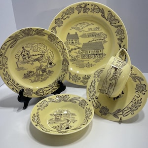 May include: A vintage yellow and brown dish set featuring a rural scene design. The set includes a dinner plate, salad plate, bowl, cup, and saucer. The plates and bowl have a floral border.