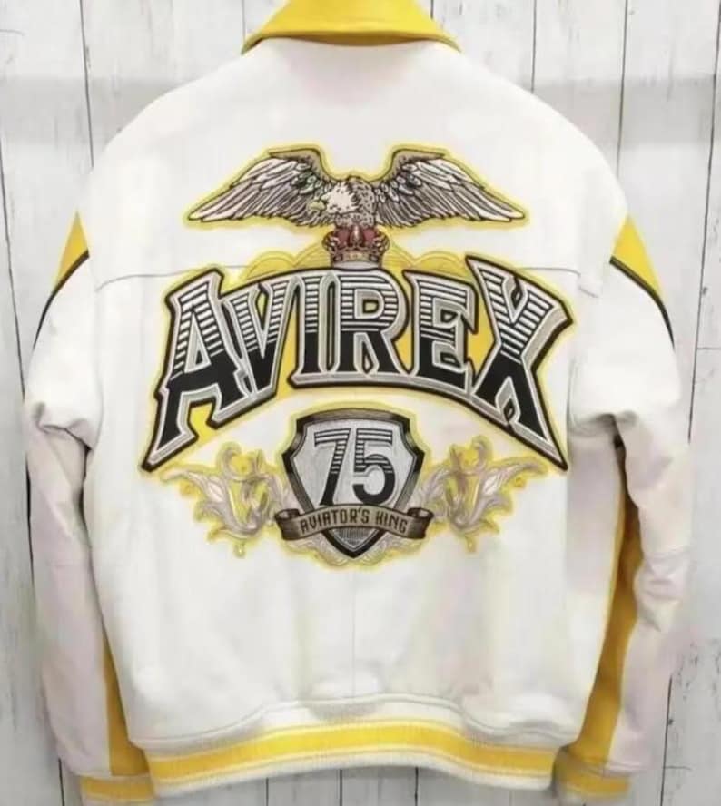May include: White leather jacket with yellow accents and the text "AVIREX" and "75 AVIATOR'S KING" on the back. Features an eagle graphic above the text. The jacket has a yellow collar and stripes.