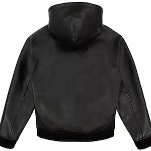 Pu&ograve; includere: Giacca in pelle nera con cappuccio. La giacca ha orlo e polsini a coste. Il cappuccio &egrave; attaccato alla giacca ed &egrave; realizzato nello stesso materiale in pelle nera. La giacca &egrave; in stile bomber.