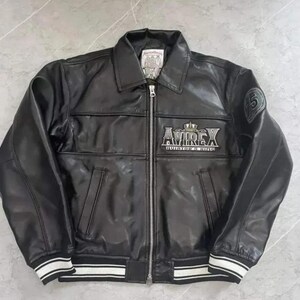 May include: Black leather jacket with a zip-up front, collar, and white striped cuffs. The jacket features the "AVIREX" logo in silver lettering on the chest and a patch on the sleeve. A classic bomber style.