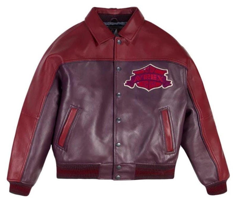 Puede incluir: Chaqueta de cuero burdeos y morado con cierre de botones, cuello y pu&ntilde;os y dobladillo acanalados. La chaqueta presenta un parche en el pecho con la palabra "AVIREX" en un dise&ntilde;o estilizado. Dos bolsillos delanteros.