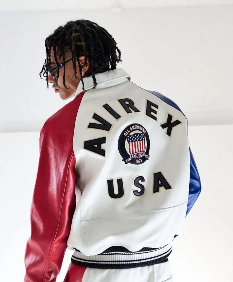 May include: White, red, and blue leather jacket with the text "AVIREX" and "USA" on the back. The jacket features a patch with the words "ALL AMERICANS" and the American flag. The sleeves are red and blue.